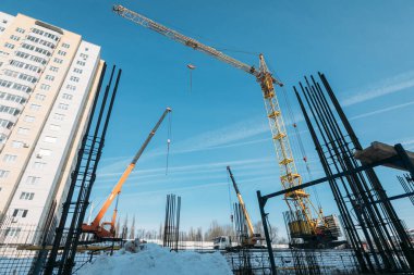 Sarı vinçler ve güneşli kış mevsiminde çok katlı bir konutun temeli.