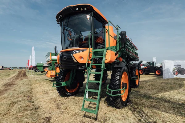 orange tractor sprayer in a field at an agricultural trade show