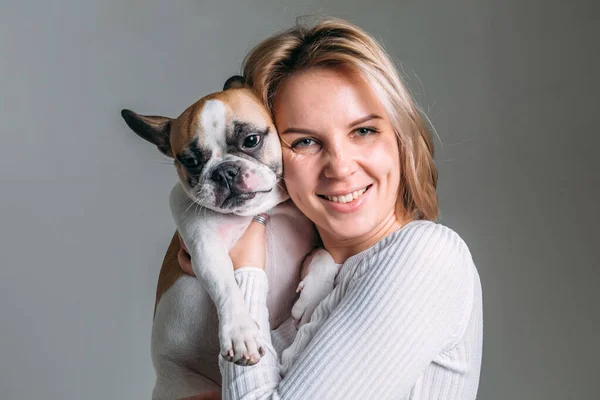 French bulldog and his mistress girl in a white jacket in the studio on a white background play