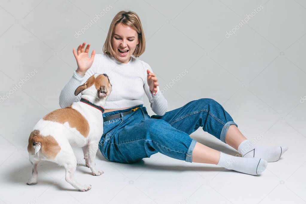 one young girl plays with her funny french bulldog in the studio with a white background