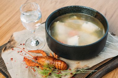 Bir restoranda ahşap bir tepside Rus balık çorbası, haşlanmış kerevit ve bir bardak votka ile servis edilir.