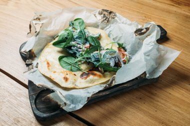 Etli, sebzeli, soslu ve otlu taze pide bir tortilla ve bir restoranda ahşap tepside servis edilir.