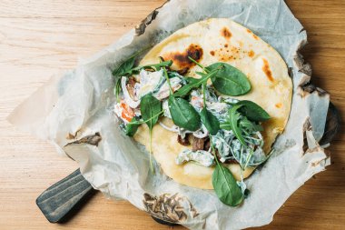 Etli, sebzeli, soslu ve otlu taze pide bir tortilla ve bir restoranda ahşap tepside servis edilir.