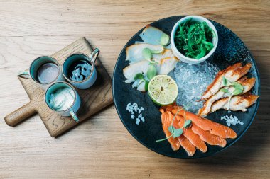 Limonlar, yosunlar ve soslarla dolu büyük bir tabakta çeşitli balık tabakları.