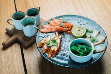 Limonlar, yosunlar ve soslarla dolu büyük bir tabakta çeşitli balık tabakları.