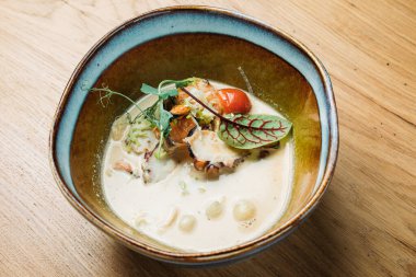 Balık, deniz ürünleri, sos ve sebzelerle dolu derin bir tabakta balık sosu bir restoranda servis edilir.