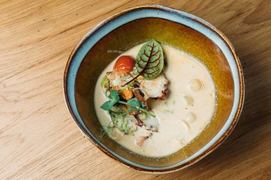 Balık, deniz ürünleri, sos ve sebzelerle dolu derin bir tabakta balık sosu bir restoranda servis edilir.