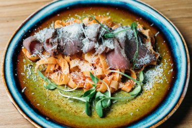 Pastırma ve domates soslu geleneksel İtalyan makarna rendelenmiş parmesan peyniri serpiştirilmiş.