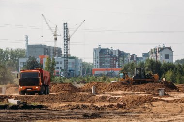 Turuncu damperli kamyon güneşli bir günde inşaat alanında kum taşır.