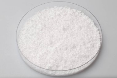 Cam laboratuvar kavanozunda beyaz arka planda gevşek beyaz sentetik kauçuk örnekleri var.