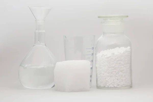 玻璃实验室瓶 装有松散的白色合成橡胶样品 旁边有一个白色背景的白色橡胶立方体 — 图库照片