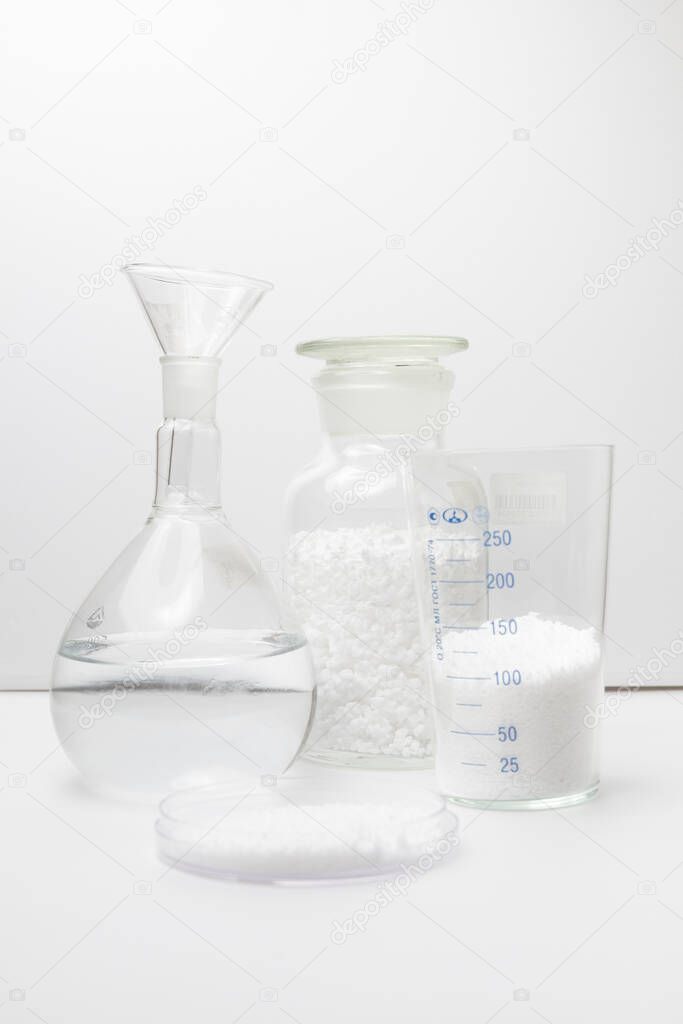 glass laboratory jar with samples of loose white synthetic rubber on a white background