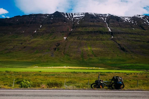 冰岛第一条沥青路 夏天的时候 一辆背负着背包的自行车停在路边 背景是群山环抱 — 图库照片