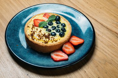 Böğürtlenli küçük tart, kafede dilimlenmiş mavi tabakta Bizet.