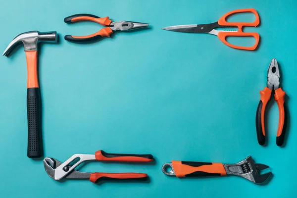 group a bunch of tools with orange handles on a blue background laid out neatly