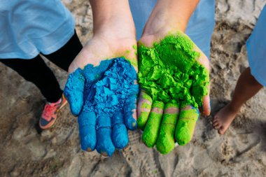 Çocukların elleri mavi ve yeşil renklerle Öğleden sonra neşeli renkler festivalinde Holi