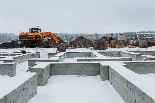 在冬季建造一座公寓楼地基的背景下 黄土挖掘机与土一起工作 — 图库照片