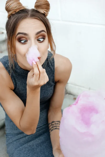 Young brunette eating cotton candy outdoors — Stock Photo, Image