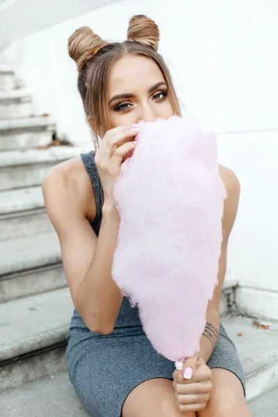Young brunette eating cotton candy outdoors — Stock Photo, Image