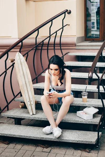 Mode mooi meisje met skateboard met smartphone — Stockfoto
