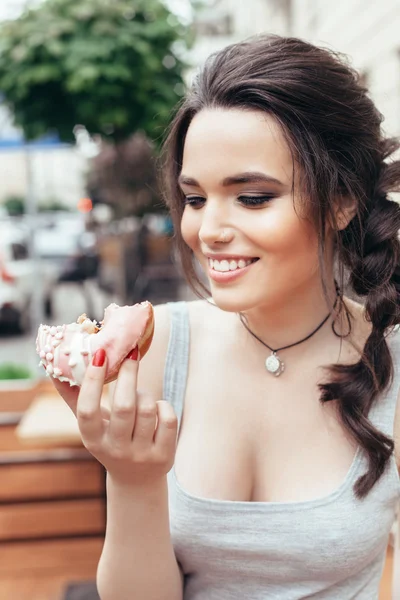 Feliz chica sonriente comiendo un donut — Foto de Stock
