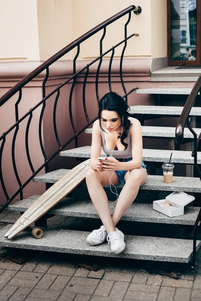 Mode mooi meisje met skateboard met smartphone — Stockfoto