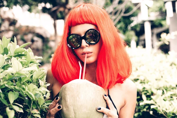 Kvinna i röd peruk dricka kokosnöt juice — Stockfoto