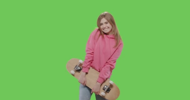 Жінка в рожевому светрі тримає скейтборд — стокове відео