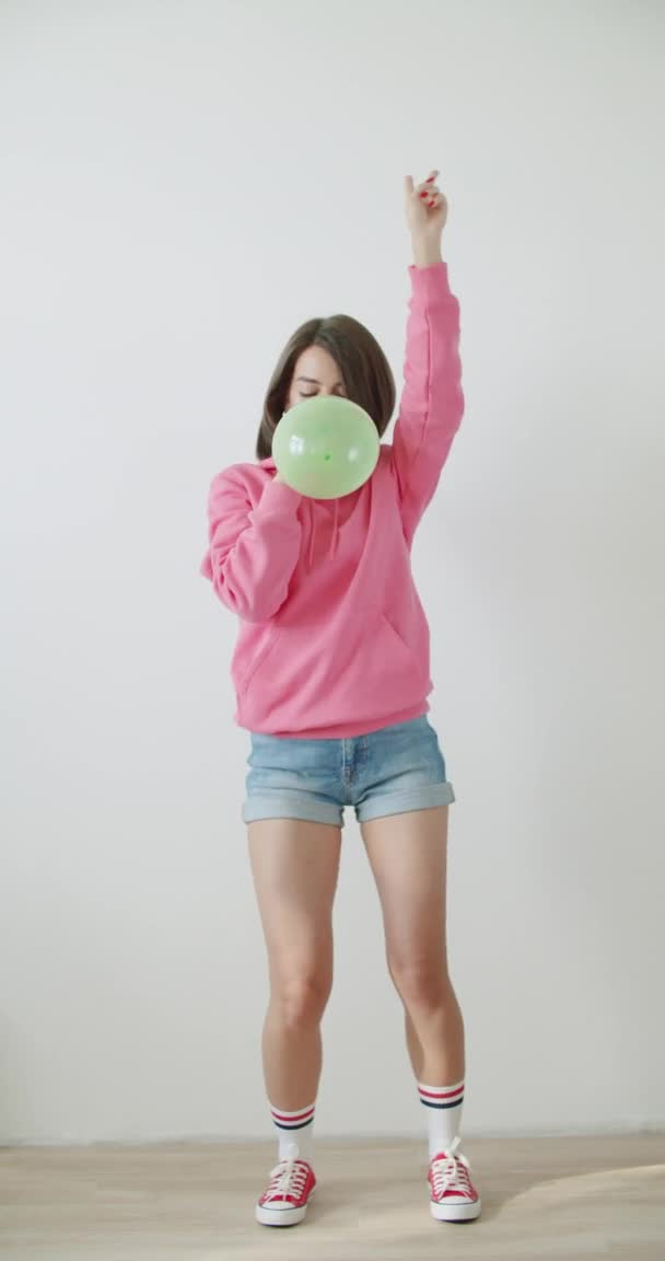 Νεαρή γυναίκα φυσάει μπαλόνι — Αρχείο Βίντεο
