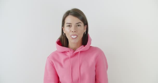 Flicka klädd i rosa hoodie blåser tuggummi — Stockvideo