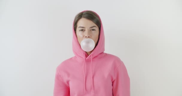 Girl dressed in pink hoodie blowing bubblegum — Stock Video