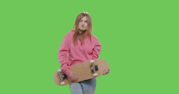 Женщина в розовой толстовке держит скейтборд — стоковое видео