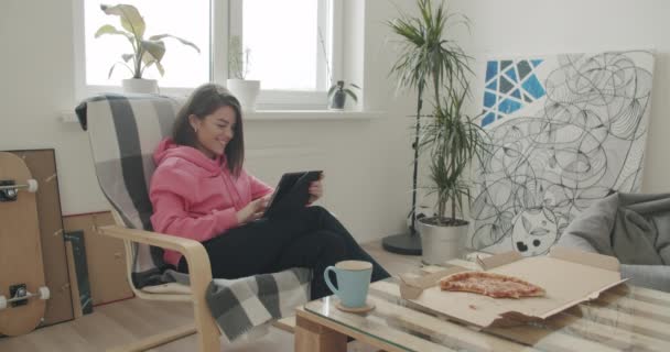 Женщина отдыхает дома, держа цифровой планшет — стоковое видео