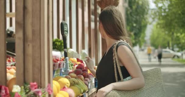 Young woman choosing fruits in street kiosk — Stock Video