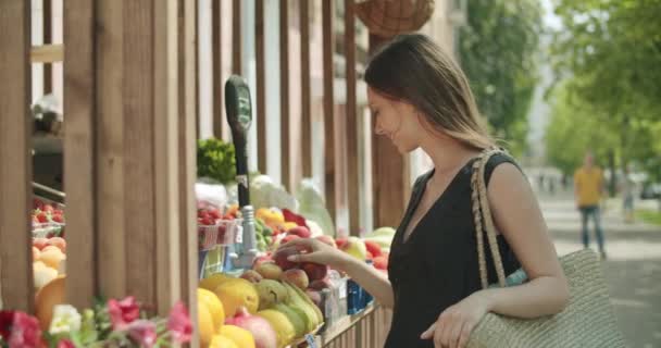 Jeune femme choisissant des fruits dans la rue kiosque — Video