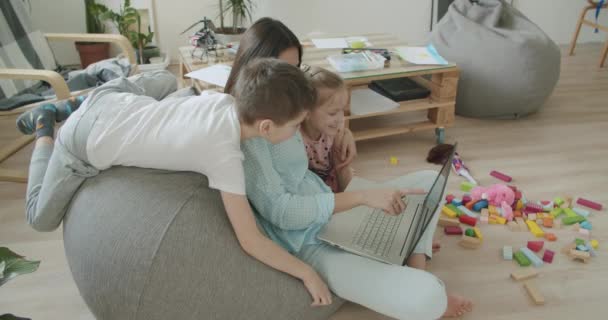 Ευτυχισμένη μαμά και χαριτωμένα παιδιά που χρησιμοποιούν φορητό υπολογιστή στο σπίτι — Αρχείο Βίντεο