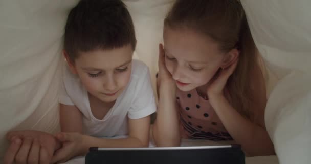 Мальчик и девочка лежат под одеялом с табличкой — стоковое видео