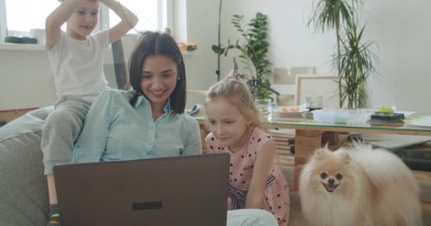 Ευτυχισμένη μαμά και χαριτωμένα παιδιά που χρησιμοποιούν φορητό υπολογιστή στο σπίτι — Αρχείο Βίντεο