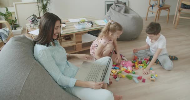 Щаслива мама і милі діти використовують ноутбук вдома — стокове відео