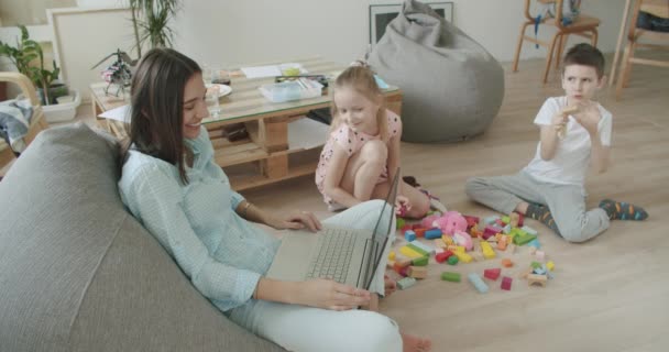 Happy mom and cute kids using laptop at home — Stock Video