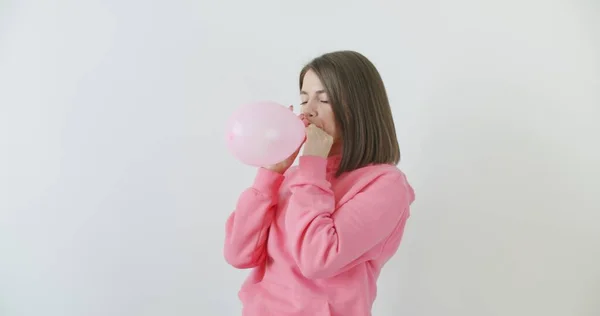 Young woman blowing a pink balloon — Stock Photo, Image