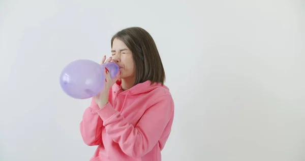 Young woman blowing a pink balloon — Stock Photo, Image