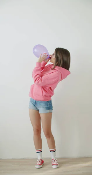 Jeune femme soufflant un ballon rose — Photo