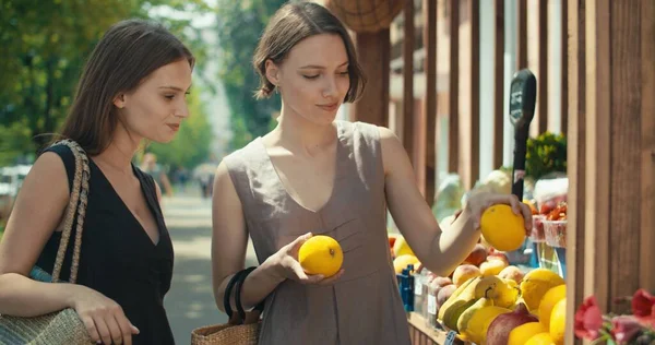 Dos mujeres eligiendo frutas en kiosco de la calle —  Fotos de Stock