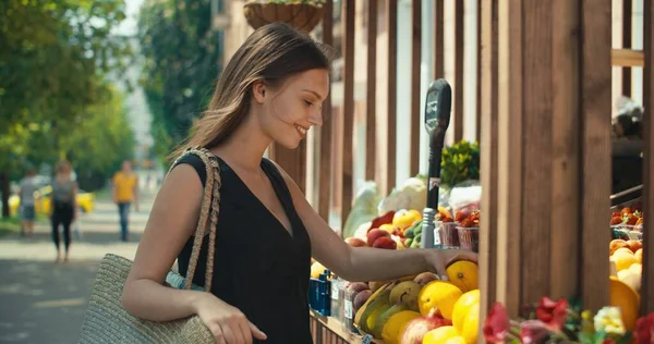 Žena vybírá ovoce v pouličním kiosku — Stock fotografie