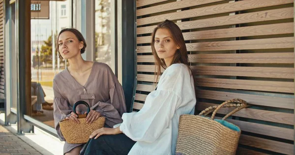 Two young women communicating while waiting at bus stop — Stock Photo, Image