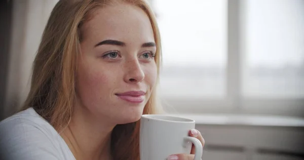 Žena pije horký čaj nebo kávu v ranním světle — Stock fotografie