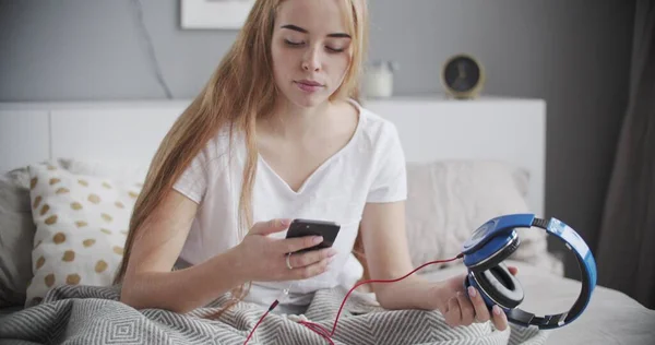Fiatal nő használ okostelefon feküdt az ágyon — Stock Fotó