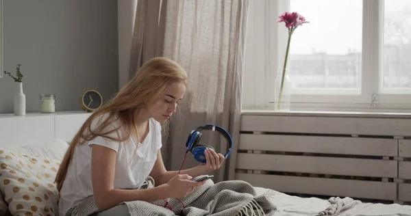 침대 위에서 스마트 폰을 사용하는 젊은 여자 — 스톡 사진