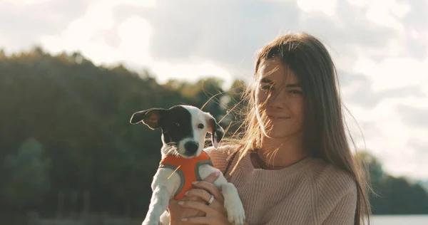 Genç kadın göl kıyısında köpekle oynuyor. — Stok fotoğraf